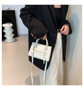 Close-up of white leather handbag featuring fashion tassel zipper and gold hardware detail