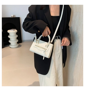 Detail of a beige crossbody square bag with metal zipper and long leather puller