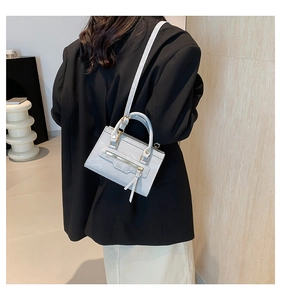 Detail of light grey glossy leather crossbody bag with front zipper on black suit