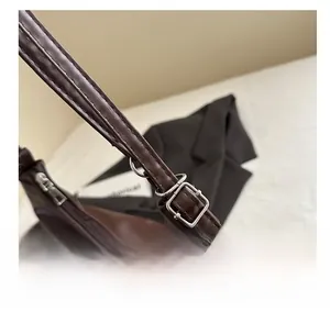 Detailed close-up of adjustable metal buckle and stitching on brown leather shoulder bag