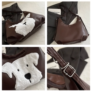 Detail of plush dog embroidery and adjustable silver buckle on a brown PU tote bag