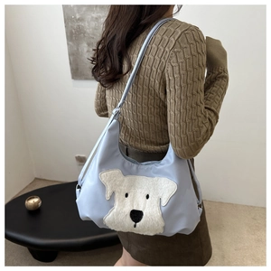 Light blue nylon tote bag with plush dog embroidery worn by a model in casual style