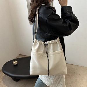 Creamy white oversized drawstring tote bag with dual front pockets for autumn commute