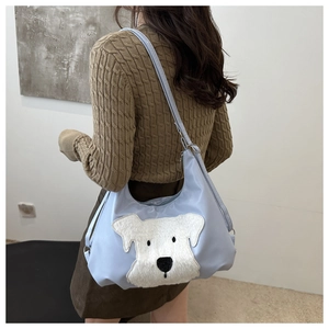 Détail du cabas bleu clair avec écusson chiot en peluche blanche et large bandoulière