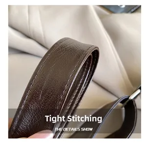 Close-up of tight stitching and lychee grain texture on dark brown leather shoulder strap