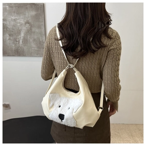 Vue détaillée d'un sac cabas en cuir crème avec motif chien porté par un mannequin