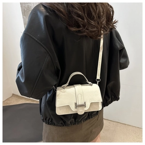 Rear view of a model wearing a cream leather crossbody square bag with silver buckle