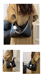Detail of a black leather hobo bag with plush charm styled with a khaki trench coat