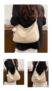 Detail of beige hobo shoulder bag featuring a cute white plush monster charm accessory