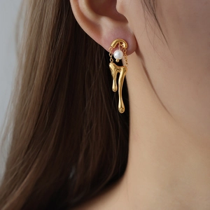 Pendientes geométricos de oro efecto lava fundida con perla de nacre usados en un modelo