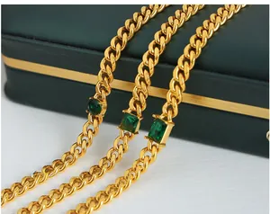 Close-up of golden Cuban link chains with emerald green zircons on a jewelry box