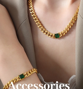 Close-up of emerald green zircon pendant with gold cuban chain on a fashion model