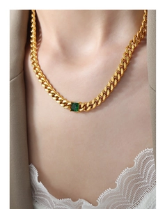 Detail of a vintage gold Cuban chain necklace with a square emerald-cut green gemstone