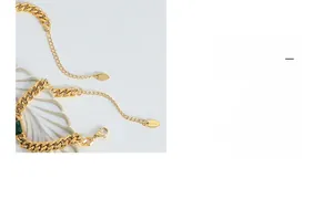 Detailed close-up of gold chunky chain with green gemstone and K18 hallmark tag