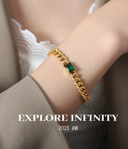 Macro view of gold-plated thick chain bracelet with emerald green zircon stone on wrist