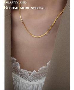 Detalle de una elegante cadena plana de serpiente dorada lucida con una chaqueta