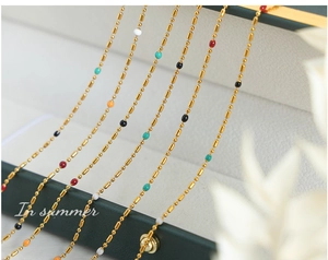 Detail of colorful beads and gold titanium steel chains with boho enamel accents
