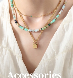 Close-up of triple-layered gold necklaces with bead strand and square lock pendant