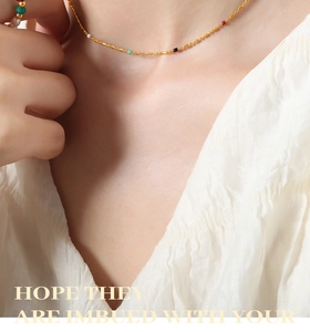 Detail of titanium steel gold chain necklace featuring colorful beads on a collarbone view