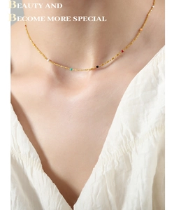 Detail of a vintage gold titanium steel necklace featuring colorful beads on a delicate chain