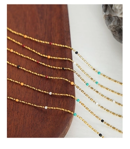 Detail of gold bead chain necklace featuring colorful enamel beads and polished finish