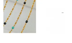 Macro shot of titanium steel chain with gold beads and turquoise enamel accents