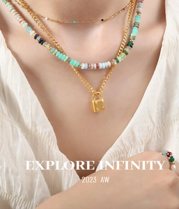 Close-up of layered necklaces with turquoise, red agate beads and a gold lock pendant