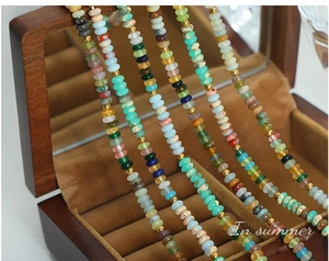 Détail de perles colorées et d'entretoises plaquées or sur un collier bohème dans un coffret