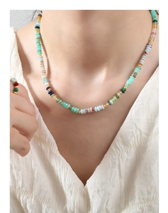 Détail d'un collier en perles de pierres fines et bague assortie portée par un modèle