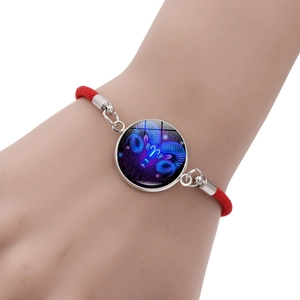 Detailed close-up of a red braided Aries zodiac bracelet on a wearer's wrist