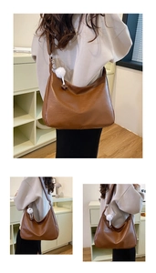 Detail of hobo bag in brown faux leather with a white fuzzy pom-pom charm decoration