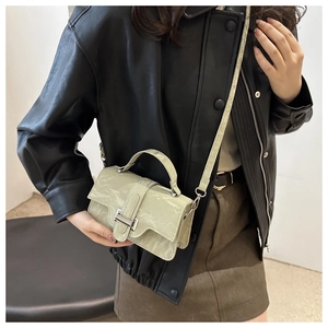 Detail of light green wrinkled texture crossbody bag with silver buckle worn by model