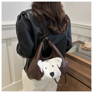 Detail of dark brown shoulder bag featuring a cute white plush puppy head decoration