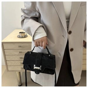 Close-up of black crossbody bag with pleated texture and silver buckle detail