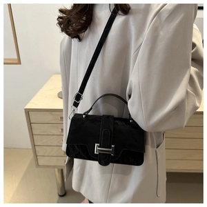 Detail of a black textured leather bag with a vintage silver buckle worn by a model