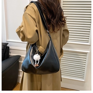 Detail der schwarzen Hobo-Schultertasche mit Plüsch-Monster-Anhänger und breitem Gurt
