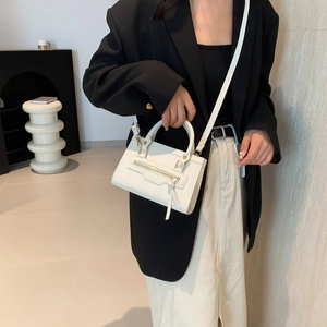 Minimalist white leather crossbody bag with top handle and decorative front zipper