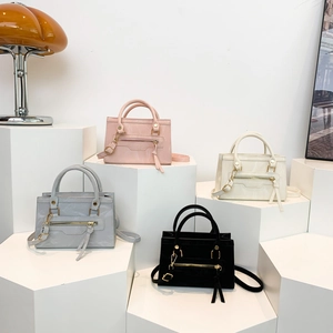 Mini square tote bags in four colors with tassels and adjustable straps on white stairs