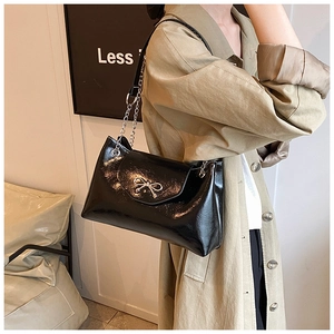 Large black patent leather tote bag with silver bow accent and metal chain strap