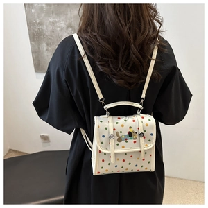 Detailed embroidery of a cartoon dog with colorful polka dots on a white mini backpack