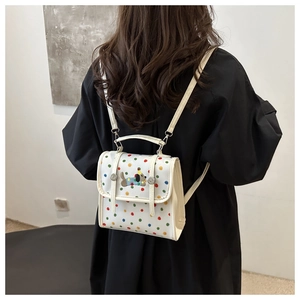 Detailed back view of a white polka dot backpack with a cute cartoon dog embroidery