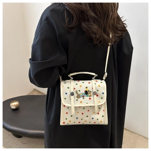 Detail showing colorful polka dots and cute dog embroidery on a white crossbody bag