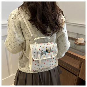 Close-up of white crossbody bag featuring colorful polka dots and cute dog embroidery patch