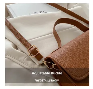 Detail of brown lychee grain leather handbag with gold adjustable metal buckle and strap