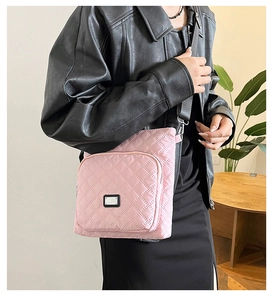 Pink quilted nylon crossbody bag with adjustable strap worn by model in casual setting