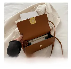 Detail of vintage brown leather handbag featuring an elegant gold magnetic buckle closure