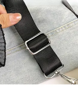 Detail of adjustable textile strap and silver metal buckle on light blue denim handbag