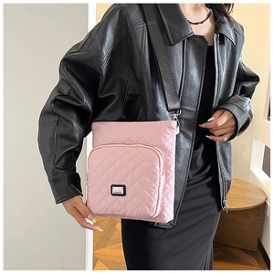 Detailed close-up of a pink quilted nylon crossbody bag featuring a black shoulder strap