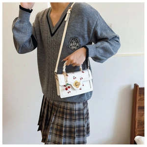 Detail of white cherry print handbag with golden flower lock and cute cherry charm