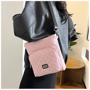 Model showing a pink quilted nylon crossbody bag with adjustable black strap and silver tag